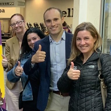 A group of Easy Mile Fitness team members give a thumbs up to the camera.